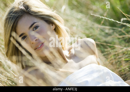Young woman leaning back in tall grass, smiling at camera Stock Photo