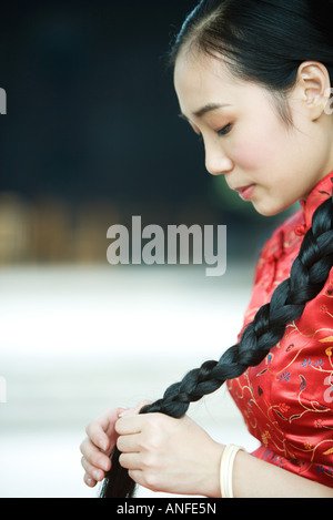Young woman wearing traditional Chinese clothing, holding long braid Stock Photo