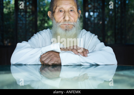 Elderly man wearing traditional Chinese clothing, arms folded, looking at camera, portrait Stock Photo