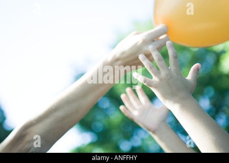 Boy and mother reaching for balloon, cropped view of arms Stock Photo