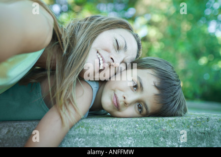 Boy and mother lying down, woman resting head on boy, boy smiling at camera Stock Photo