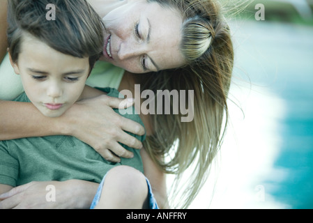 Boy and mother, woman hugging son from behind Stock Photo