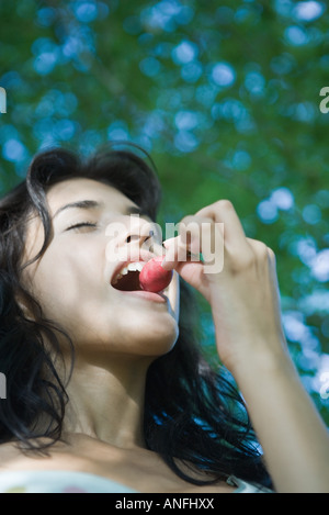 Young woman biting into radish, low angle view Stock Photo