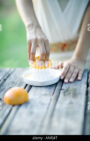 Woman pressing orange with citrus press, close-up, cropped view of hands Stock Photo