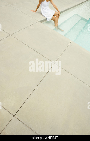 Woman sitting on edge of pool, feet in water, high angle view, cropped Stock Photo