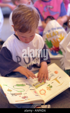 Boy age 5 reading at the public library on family day. Merriam Park Library St Paul Minnesota USA Stock Photo