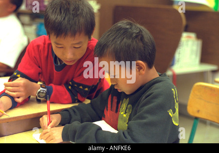 Asian American fourth graders working on homework at summer school program. Holland School Minneapolis Minnesota USA Stock Photo