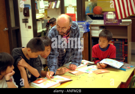 Summer school white teacher age 50 working with Asian American students age 10. Holland School Minneapolis Minnesota USA Stock Photo