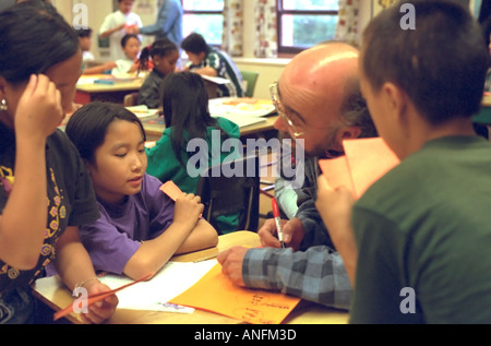 White teacher 50 working with Asian American summer school students age 10. Holland School Minneapolis Minnesota USA Stock Photo