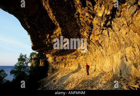 A hiker enjoys the view under Overhanging Point, Bruce Peninsula National Park, Ontario, Canada.