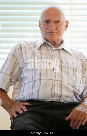 senior citizen (70-80 years old) sitting on chair in vacant house, Canada. Stock Photo