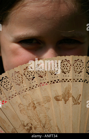 Young Girl hiding behind a fan Stock Photo