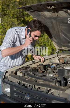 A man calls for help on a cell phone from a stranded car Stock Photo
