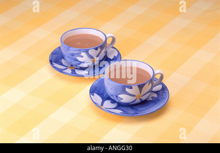 Two blue tea cups on yellow checked table cloth Stock Photo