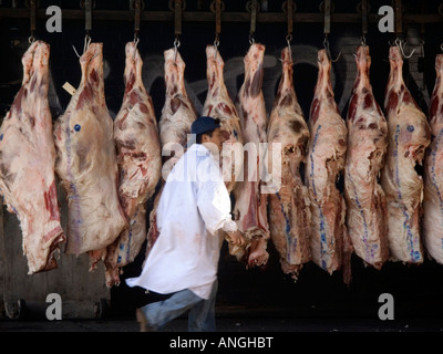 A worker passes sides of beef waiting to be delivered at a butcher in the trendy meatpacking district in NYC Stock Photo