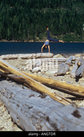 Woman doing a cartwheel on log, Revelstoke, British Columbia, Canada. Stock Photo