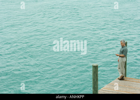 Man standing on dock listening to mp3 player, high angle view Stock Photo