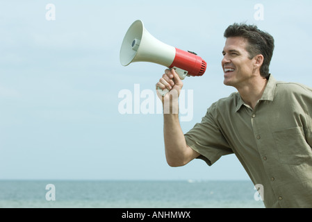 Man using megaphone, ocean horizon in background Stock Photo