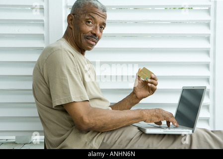 Senior man making credit card purchase online, smiling at camera Stock Photo
