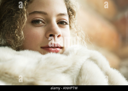 Teen girl under soft blanket, smiling at camera, close-up Stock Photo
