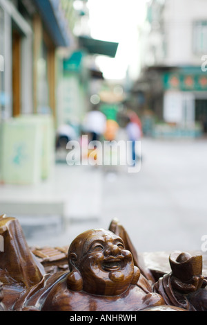 Laughing Buddha statue, street in background Stock Photo