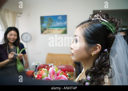 Bride wearing veil, sprig of evergreen in hair, in home interior, profile Stock Photo