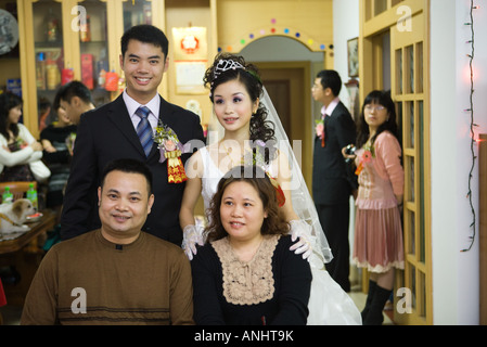Bride and groom standing behind couple, smiling, portrait Stock Photo