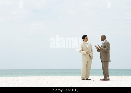 Two businessman standing on beach having conversation Stock Photo