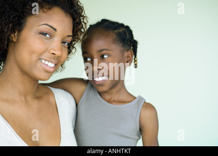 Young woman holding daughter, smiling at camera, cropped view Stock Photo