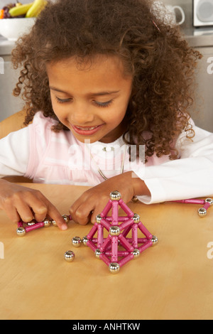 a girl smiles as she plays with a magnetic puzzle Stock Photo