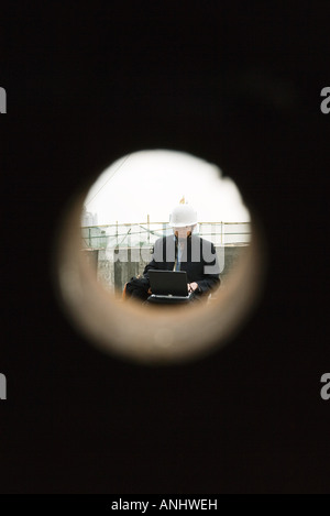 Building contractor working at construction site, seen through hole Stock Photo