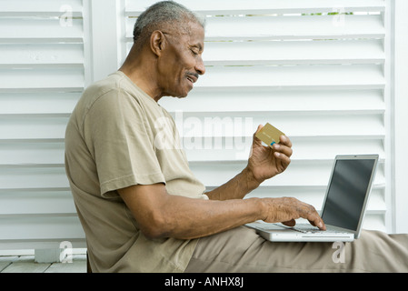 Senior man using laptop, making on-line purchase with credit card Stock Photo