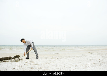 Man at the beach, bending over and digging in sand, smiling at camera Stock Photo