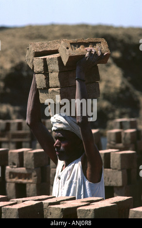 Male labourer balancing a stack of bricks on his head at a brickworks in Pune, Maharashtra, India. Stock Photo