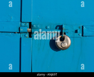 Bolt and padlock on colourful blue wooden door. Stock Photo