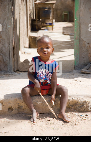 A colour portrait of a young boy sat on the roadside in a poor area of Santa Maria in the Cape Verde islands. Stock Photo