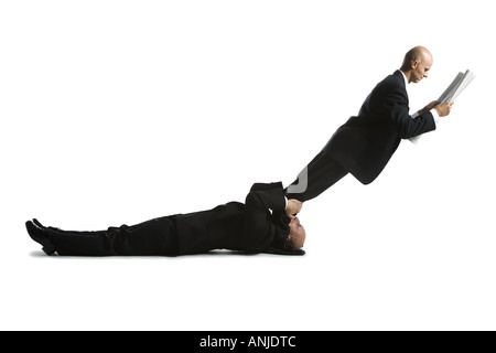 Profile of two male acrobats in business suits Stock Photo