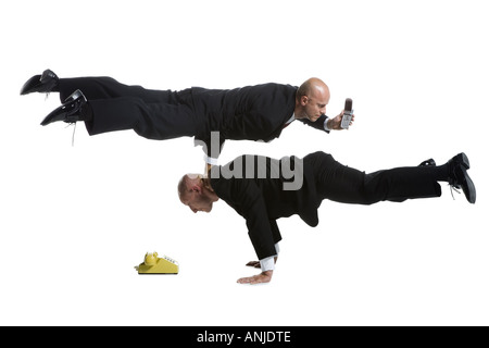 Profile of two male acrobats in business suits performing Stock Photo