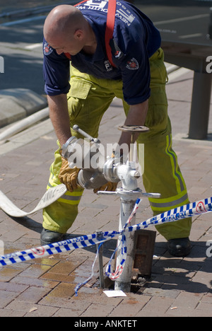 Fire fighters at work clearing up after an incident; fireman; fire fighter; attaching hose to fire hydrant; Stock Photo