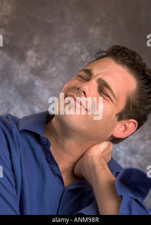 Man holds his neck in pain Stock Photo