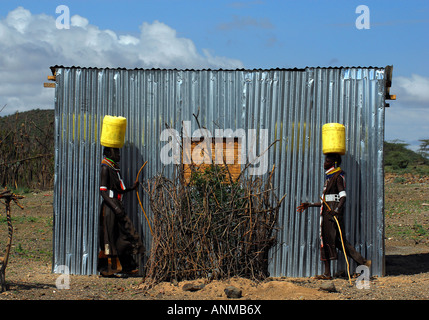 Two Turkana women carrying gerrycans on heads in symmetrical image Stock Photo