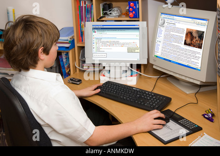 11 year old school boy doing home work on a two screen PC Stock Photo
