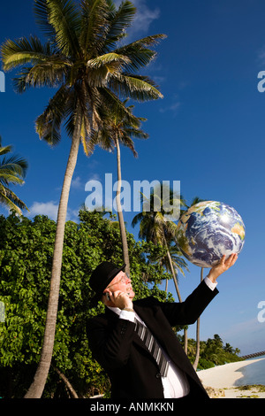Maldives businessman in bowler hat and business suit with globe in palm of hand Stock Photo