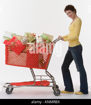 Woman pushing shopping cart of gifts Stock Photo