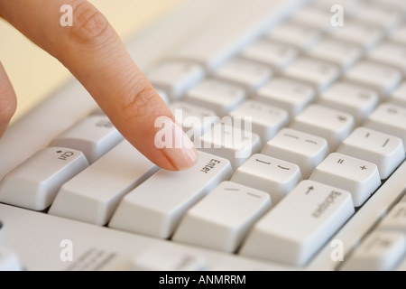 Woman pressing Enter key on computer keyboard Stock Photo