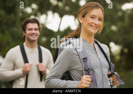 Couple wearing backpacks in woods Stock Photo