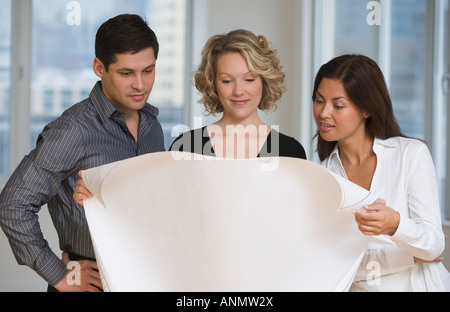 Multi-ethnic businesspeople looking at blueprints Stock Photo
