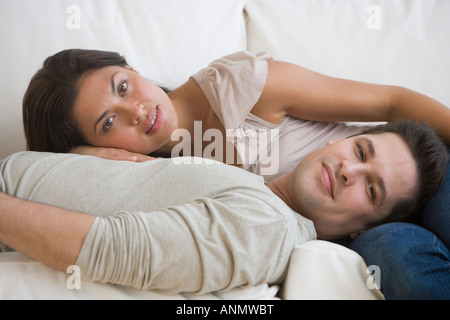 Multi-ethnic couple laying on sofa Stock Photo