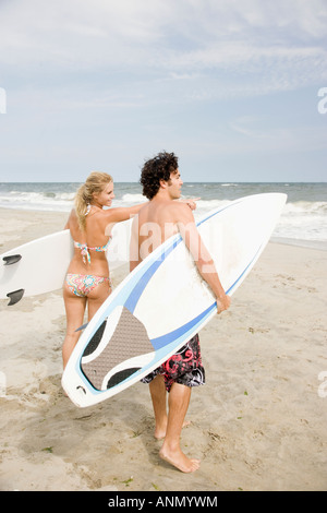 Couple holding surfboards at beach Stock Photo