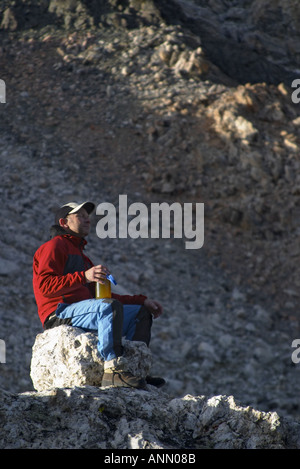 Man sitting on boulder drinking from water bottle Grand Teton Lower Saddle Grand Teton National Park Stock Photo